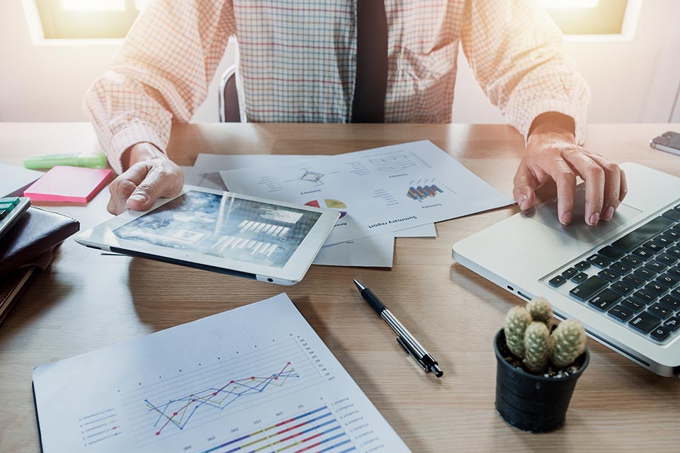 Businessman working with digital tablet and laptop and document on wooden desk in modern office.Top view Business analysis and strategy concept.