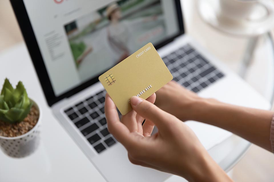 Close up woman holding golden plastic credit card mockup with number, paying online, girl using laptop, shopping online, doing internet secure payment, ordering and buying, ecommerce concept