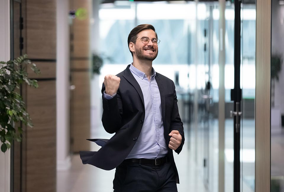 Happy young businessman dancing in office corridor celebrate business success or job promotion, excited male employee enjoy good work results or win, having Friday fun celebration, victory concept